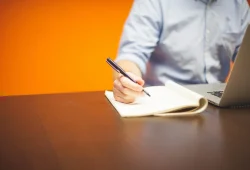 Meja kerja dengan laptop dan buku catatan untuk merencanakan niche blog