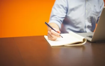 Meja kerja dengan laptop dan buku catatan untuk merencanakan niche blog