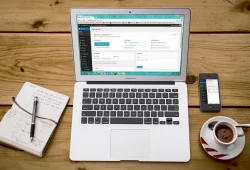 Laptop menampilkan susunan homepage blog dengan kategori dan artikel unggulan