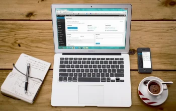 Laptop menampilkan susunan homepage blog dengan kategori dan artikel unggulan