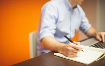 Laptop dan buku catatan di meja kerja untuk merencanakan nama dan identitas website
